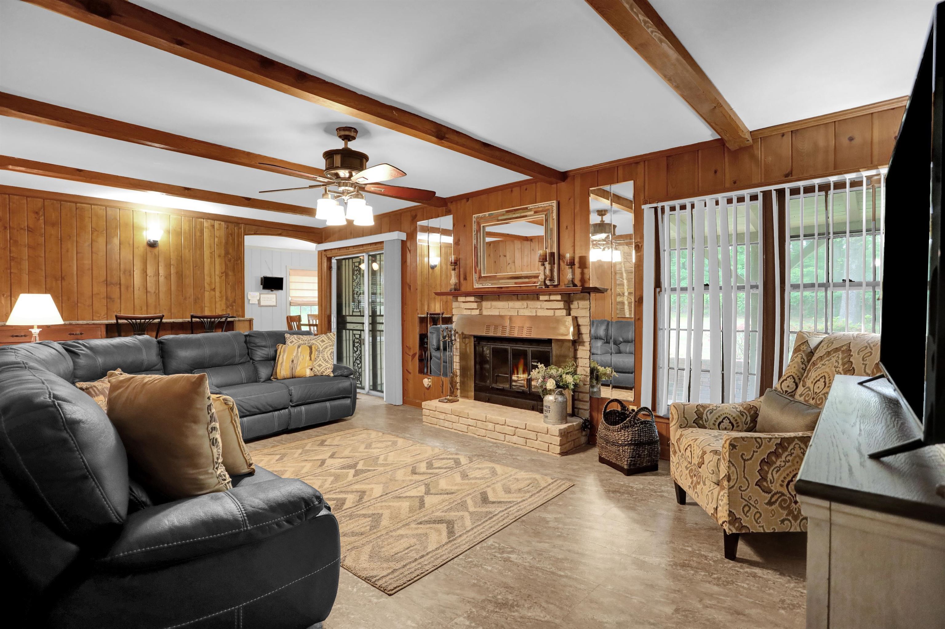 1277 Old Hickory Road Memphis, TN 38116 - Photo 10 of 29 Living area featuring wooden walls, a ceiling fan, beamed ceiling, and a fireplace