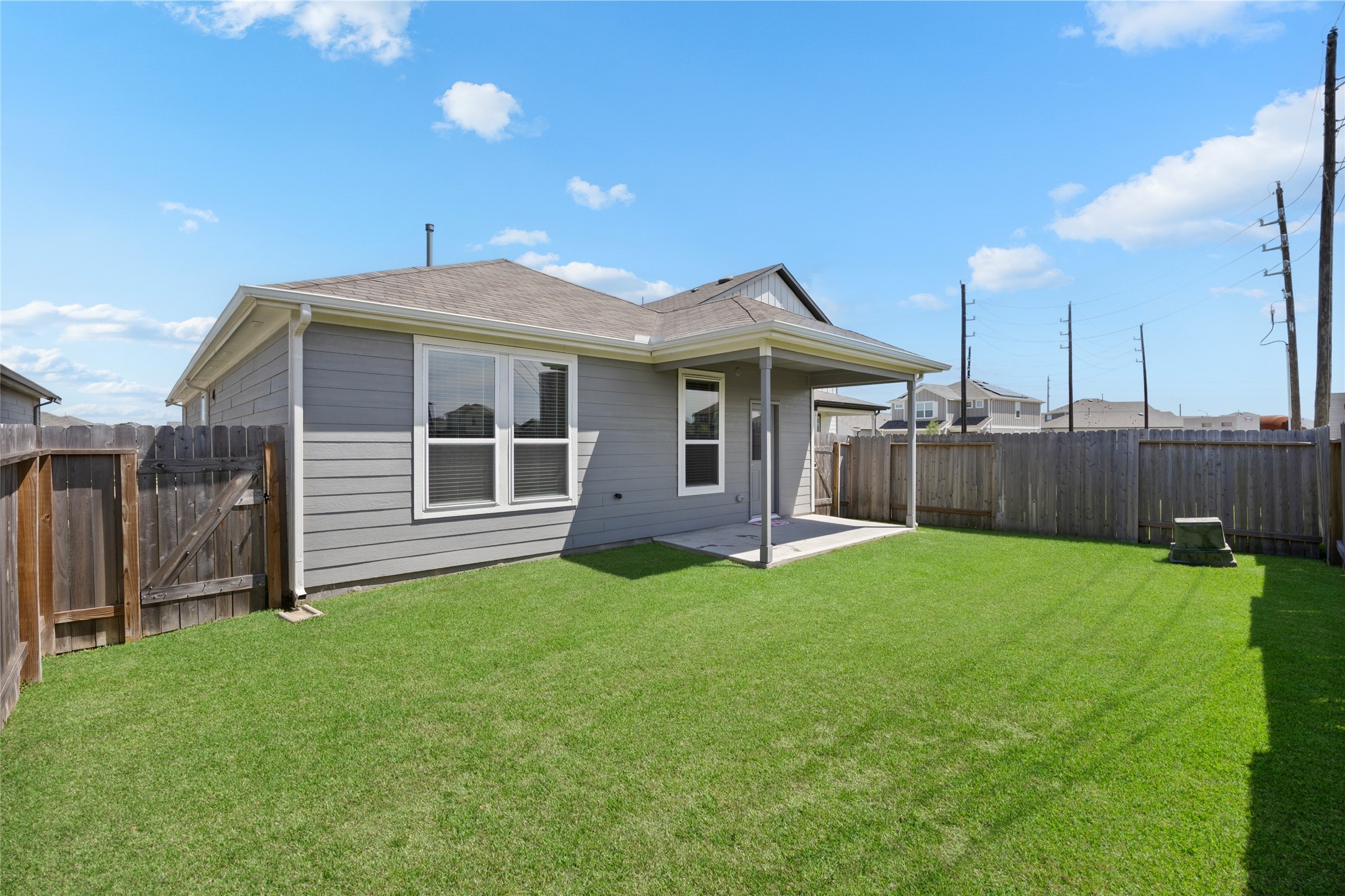 17907 Grain Auger Road Hockley, TX 77447 - Photo 24 of 24 single-story home with a neat backyard featuring a lush green lawn and a small covered patio. The area is enclosed by a wooden fence, offering privacy and a cozy outdoor space.