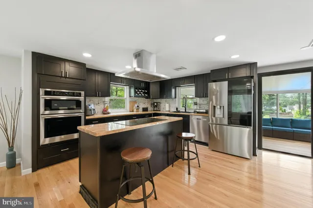 a kitchen with kitchen island a counter top space a sink stainless steel appliances and cabinets