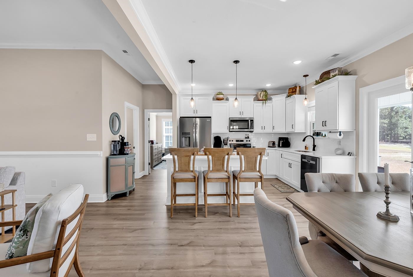 384 William Nobles Road Aynor, SC 29511 - Photo 18 of 38 Kitchen featuring crown molding, light wood-style flooring, hanging light fixtures, white cabinetry, and stainless steel appliances