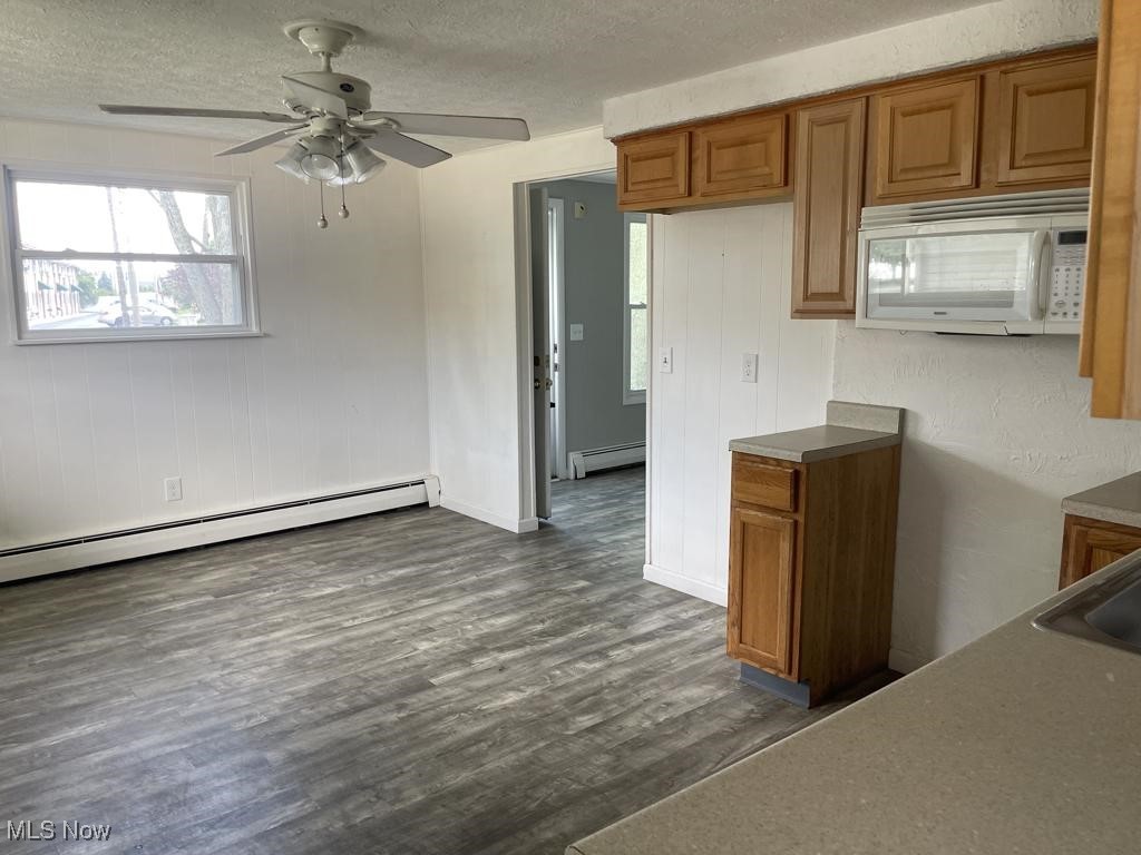 715 South Abbe Road Elyria, OH 44035 - Photo 6 of 14 Kitchen with a baseboard heating unit, ceiling fan, a textured ceiling, and dark hardwood / wood-style flooring