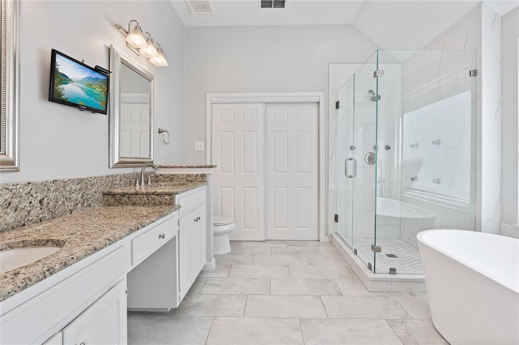 8718 Falls Road Irving, TX 75063 - Photo 17 of 28 a spacious bathroom with a granite countertop sink a toilet a mirror and shower