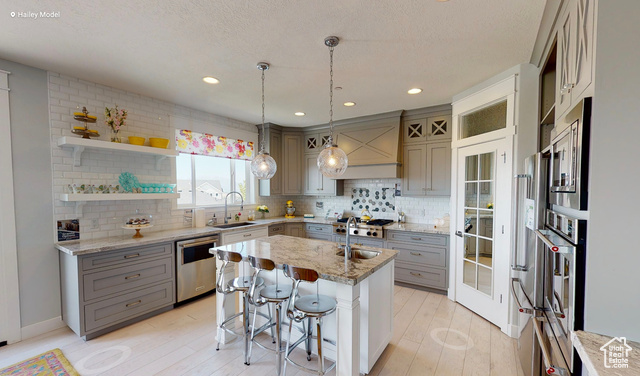 1547 North 1350 E Street, Unit 2 Mapleton, UT 84664 - Photo 7 of 18 Kitchen with gray cabinetry, stainless steel appliances, a center island with sink, tasteful backsplash, and light wood-style floors