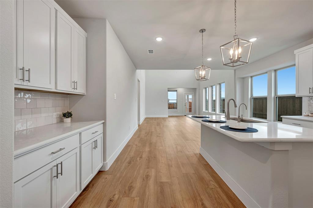 2624 Lewisville Road Celina, TX 75009 - Photo 3 of 40 a kitchen with stainless steel appliances granite countertop a sink oven and white cabinets with wooden floor