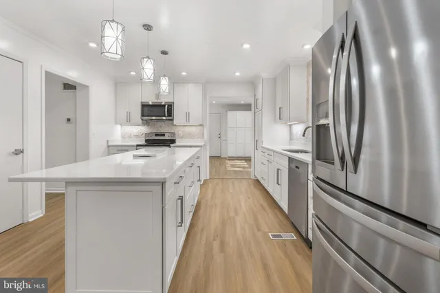 a kitchen with stainless steel appliances granite countertop a refrigerator a stove and a sink