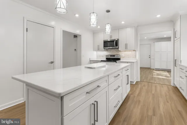 a large kitchen with kitchen island a sink dishwasher stove and white cabinets with wooden floor