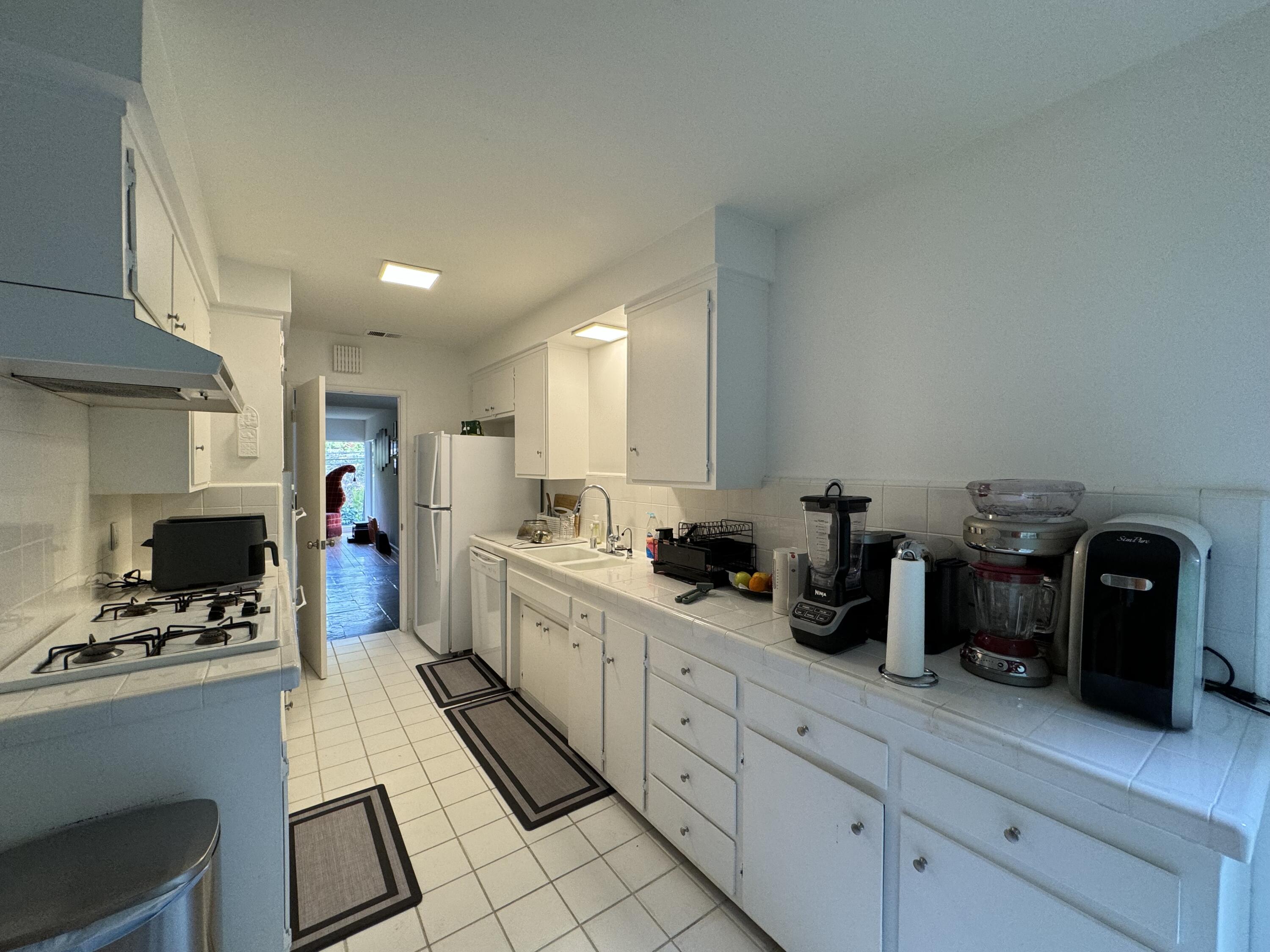 9748 Oak Pass Road Beverly Hills, CA 90210 - Photo 31 of 35 a kitchen with white cabinets and appliances