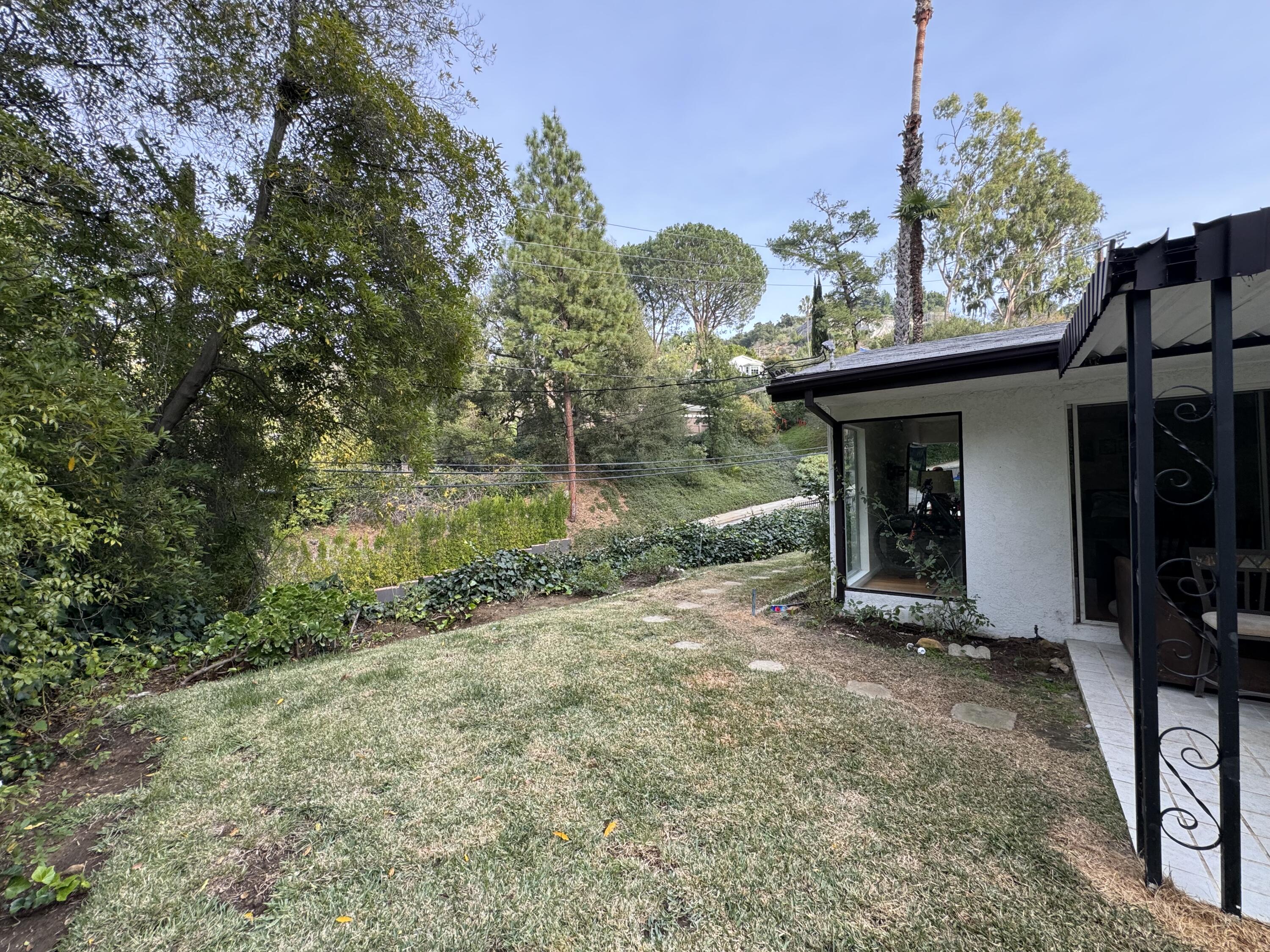 9748 Oak Pass Road Beverly Hills, CA 90210 - Photo 32 of 35 a view of a backyard with table and chairs and potted plants