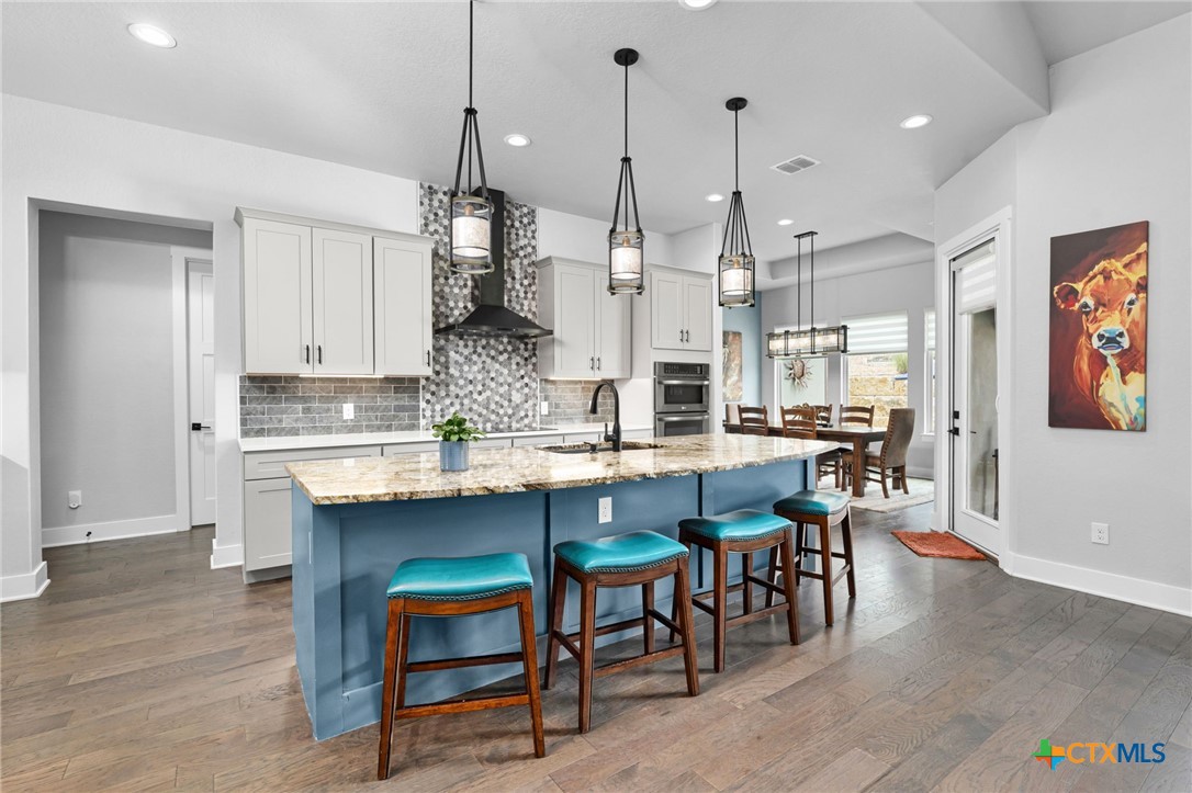 5943 Colin Ridge New Braunfels, TX 78132 - Photo 19 of 37 a kitchen with stainless steel appliances granite countertop a table chairs sink and cabinets