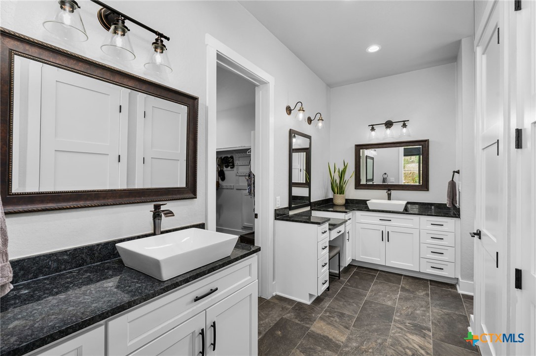5943 Colin Ridge New Braunfels, TX 78132 - Photo 26 of 37 a spacious bathroom with a granite countertop sink and a mirror