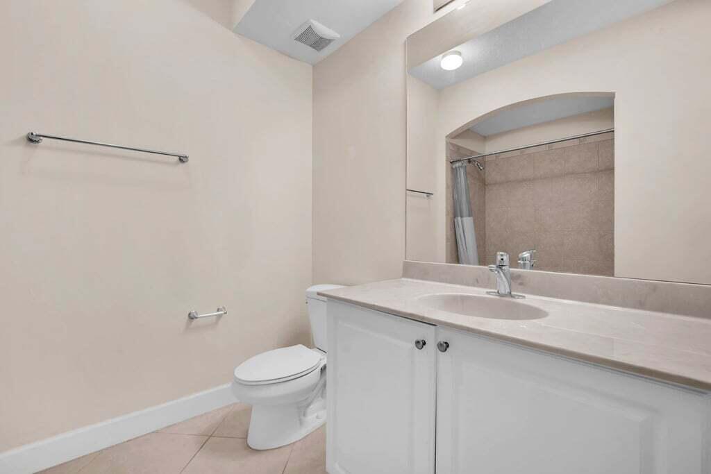 1690 Renaissance Commons Boulevard, Unit 1219 Boynton Beach, FL 33426 - Photo 21 of 38 a bathroom with a granite countertop sink a toilet and a mirror