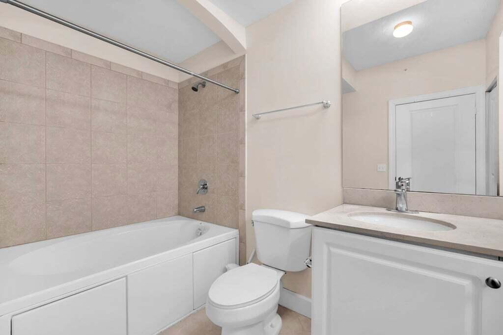 1690 Renaissance Commons Boulevard, Unit 1219 Boynton Beach, FL 33426 - Photo 22 of 38 a bathroom with a granite countertop bathtub shower sink vanity mirror and toilet