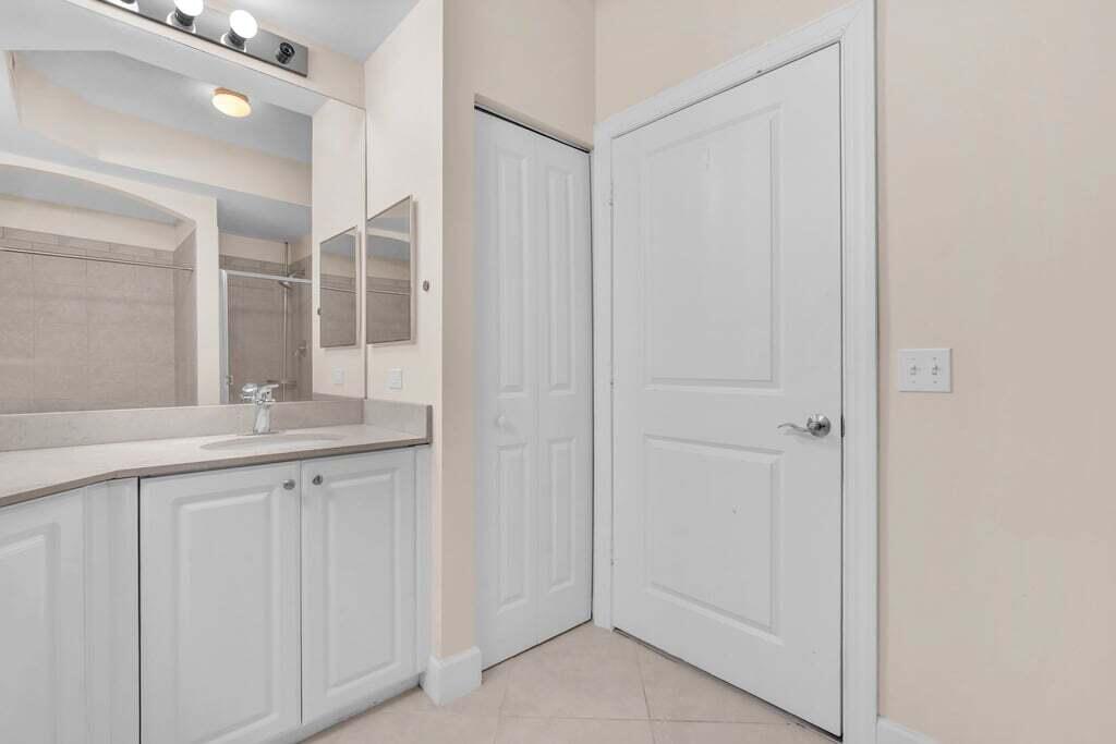 1690 Renaissance Commons Boulevard, Unit 1219 Boynton Beach, FL 33426 - Photo 28 of 38 a bathroom with a granite countertop sink and a mirror