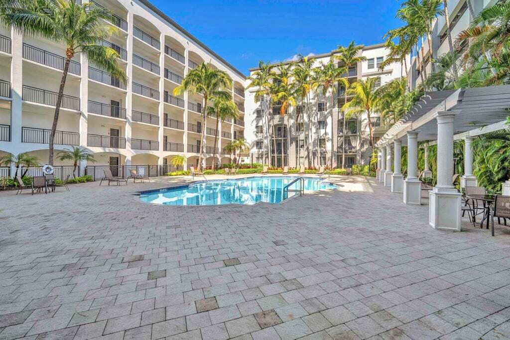 1690 Renaissance Commons Boulevard, Unit 1219 Boynton Beach, FL 33426 - Photo 33 of 38 a view of pool with lawn chairs and large trees