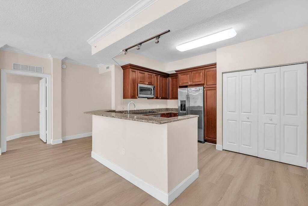 1690 Renaissance Commons Boulevard, Unit 1219 Boynton Beach, FL 33426 - Photo 8 of 38 a kitchen with stainless steel appliances granite countertop a refrigerator and a stove top oven