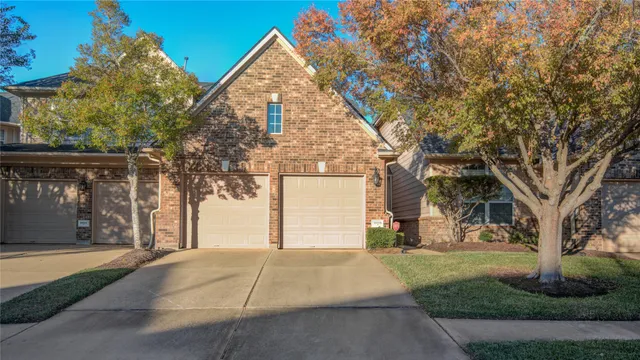 a view of brick house with a yard and large tree