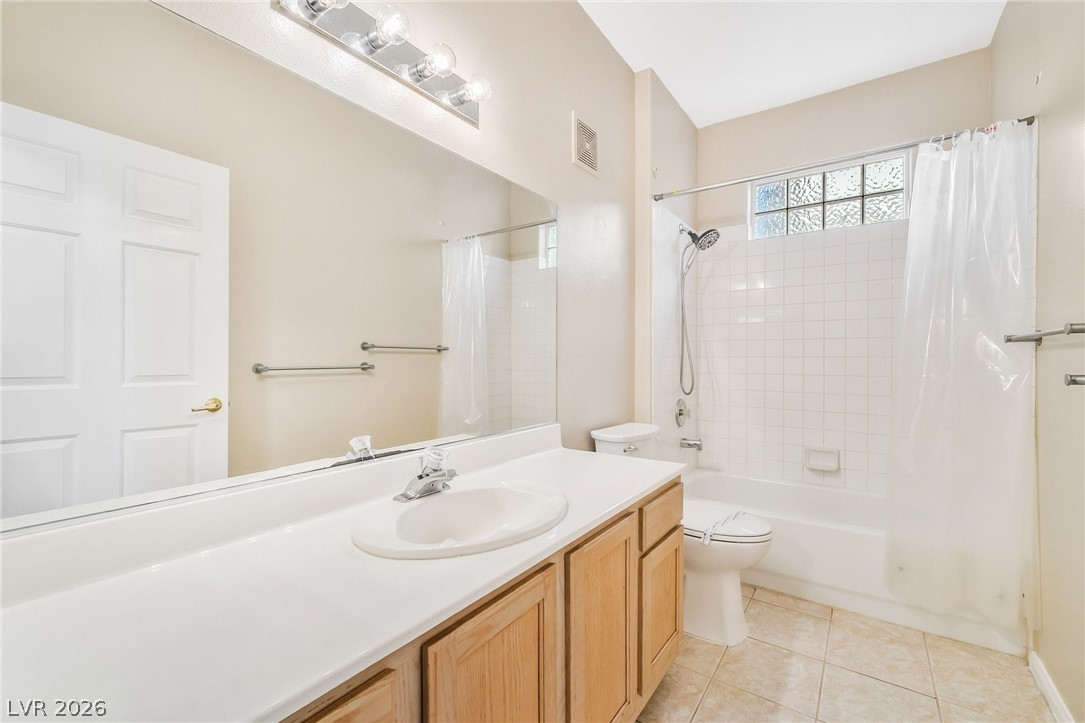 2050 West Warm Springs Road, Unit 2411 Henderson, NV 89014 - Photo 26 of 37 A pristine bathroom featuring a light wood vanity, a full mirror, and a classic tub/shower combination with tiled walls.
