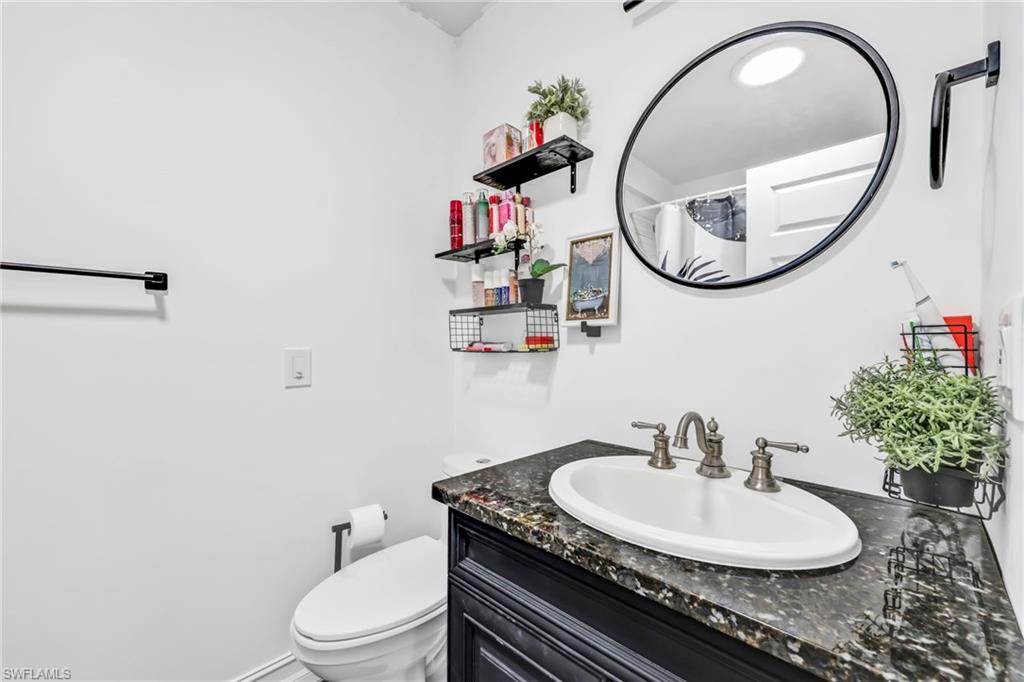 3231 13th Avenue Southwest Naples, FL 34117 - Photo 17 of 49 a bathroom with a granite countertop toilet a sink and a mirror