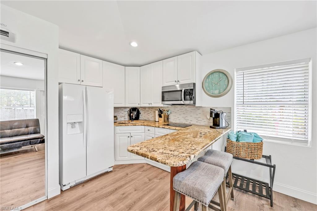 3231 13th Avenue Southwest Naples, FL 34117 - Photo 30 of 49 a kitchen with a stove a refrigerator a microwave oven with a dining table and chairs