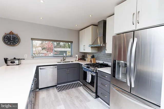 a kitchen with granite countertop stainless steel appliances a refrigerator stove top oven and sink