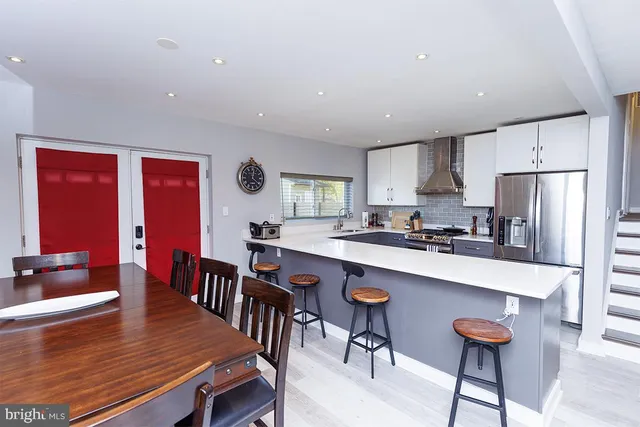 a kitchen with stainless steel appliances a dining table chairs and a refrigerator