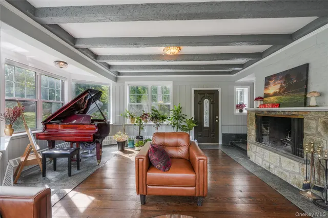 a living room with furniture a fireplace and potted plants with wooden floor