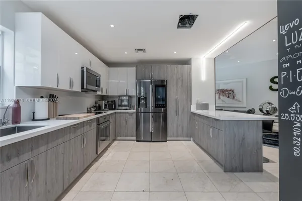 a large kitchen with stainless steel appliances kitchen island granite countertop a refrigerator and cabinets