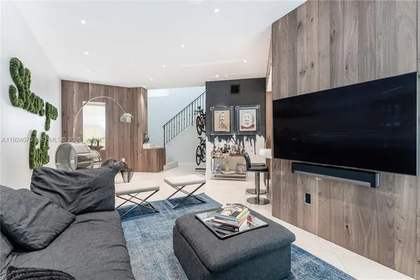 a living room with furniture a flat screen tv and kitchen view