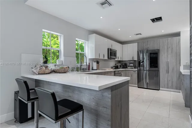 a kitchen with kitchen island a large counter top space appliances and a center island