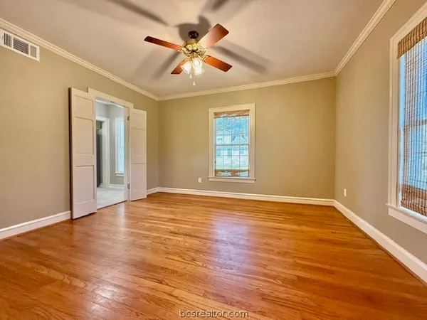 a view of an empty room with wooden floor and a window