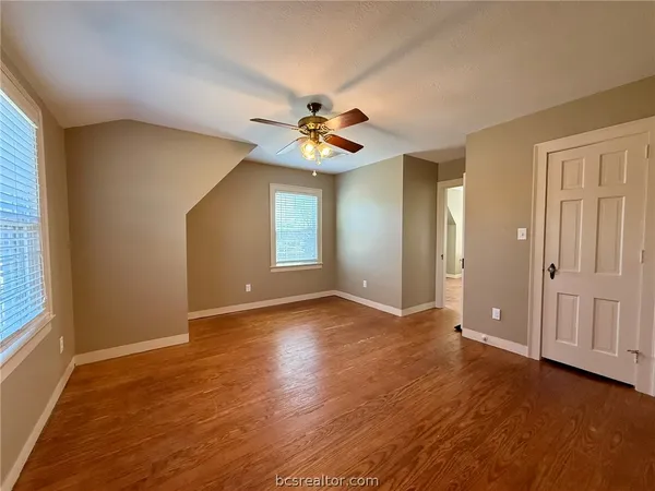 a view of an empty room with window and a ceiling fan