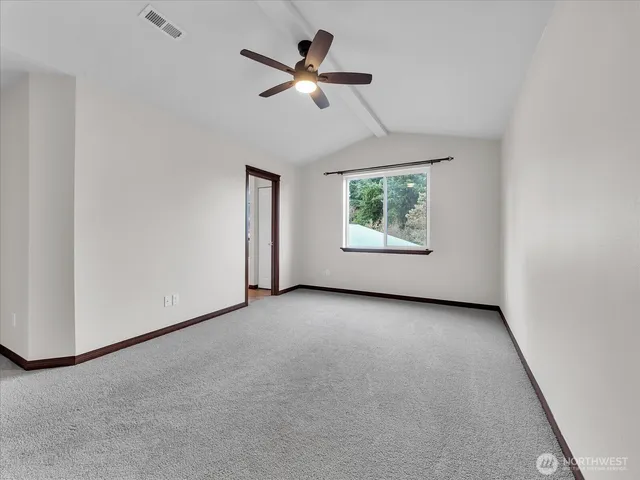 an empty room with ceiling fan and windows