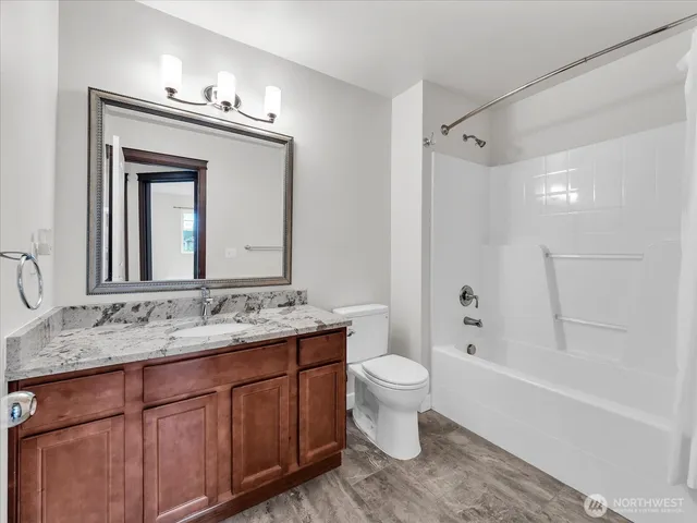 a bathroom with a granite countertop sink toilet mirror and bathtub