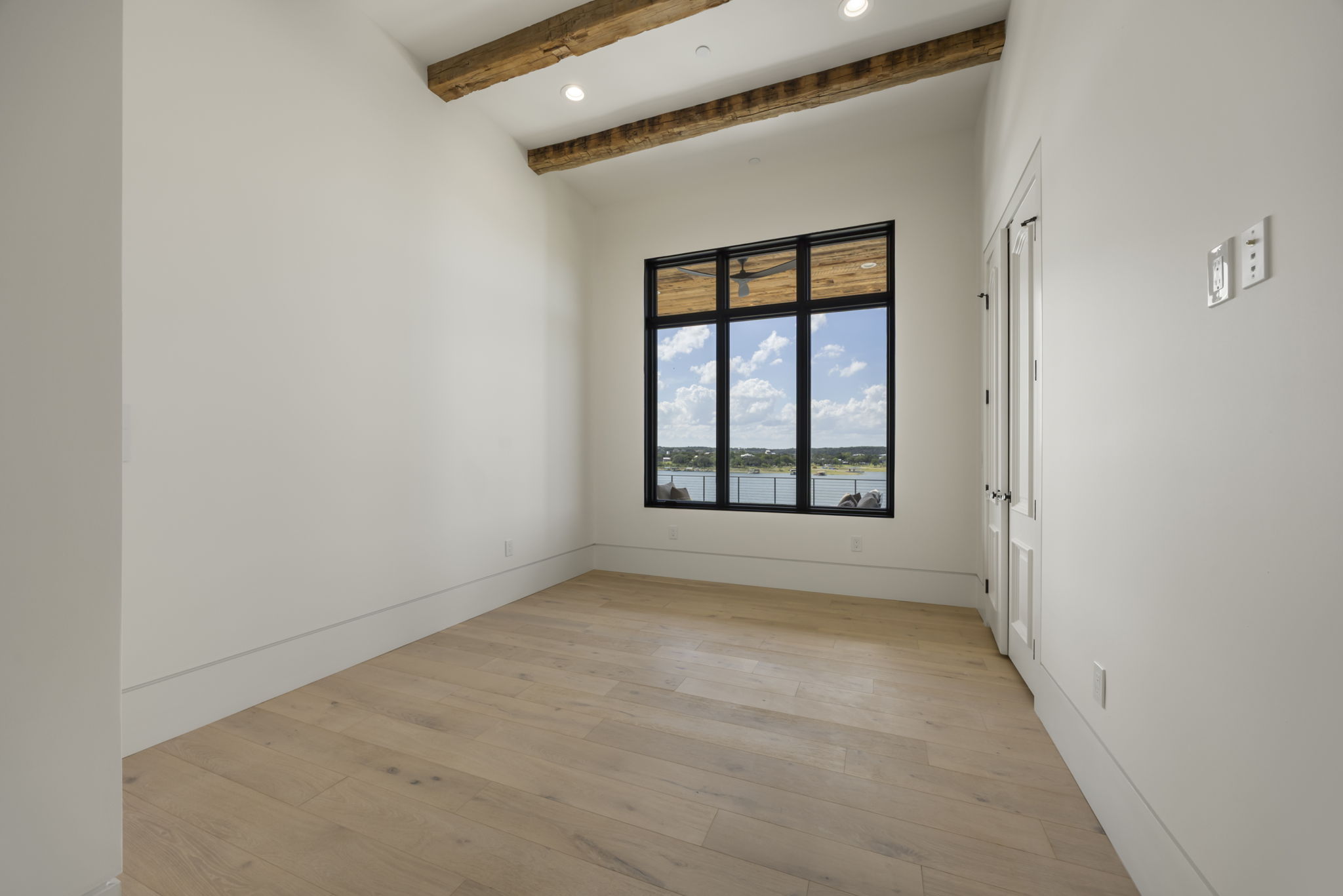 1496 Buffalo Gap Road Lakeway, TX 78734 - Photo 31 of 37 Exposed beams complement bright hardwood floors, framing a captivating water view through large windows.