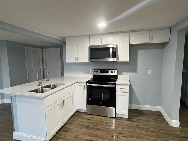 a large white kitchen with wooden floor