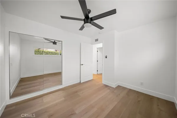 an empty room with wooden floor and ceiling fan