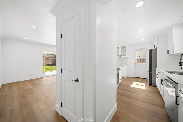 a view of a kitchen with a refrigerator a sink and dishwasher white cabinets with wooden floor