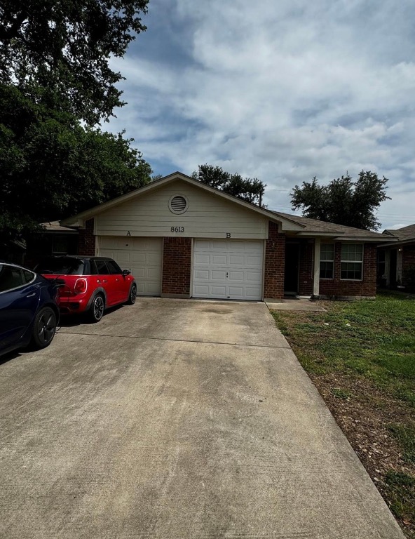 Ranch-style home with driveway, brick siding, and an attached garage
