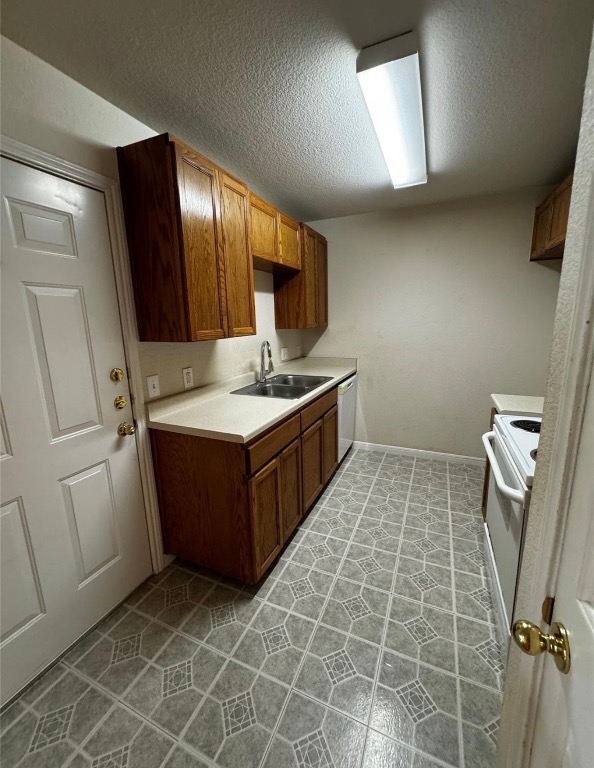 8613 Talyne Chaise Circle Austin, TX 78729 - Photo 5 of 22 Kitchen featuring light countertops, a textured ceiling, brown cabinetry, white appliances, and light tile patterned floors