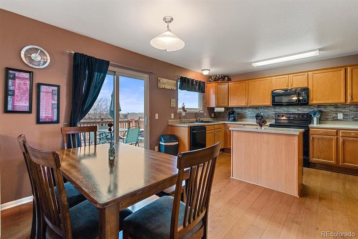 7751 Old Spec Road Peyton, CO 80831 - Photo 2 of 17 a kitchen with stainless steel appliances granite countertop a stove a refrigerator a kitchen island a dining table and chairs