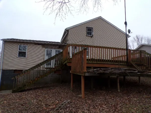 a backyard of a house with wooden deck and furniture