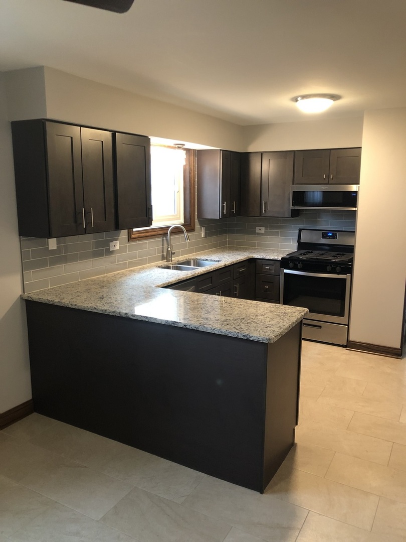 10301 McVicker Avenue Chicago Ridge, IL 60415 - Photo 5 of 21 a kitchen with kitchen island granite countertop a refrigerator and a stove