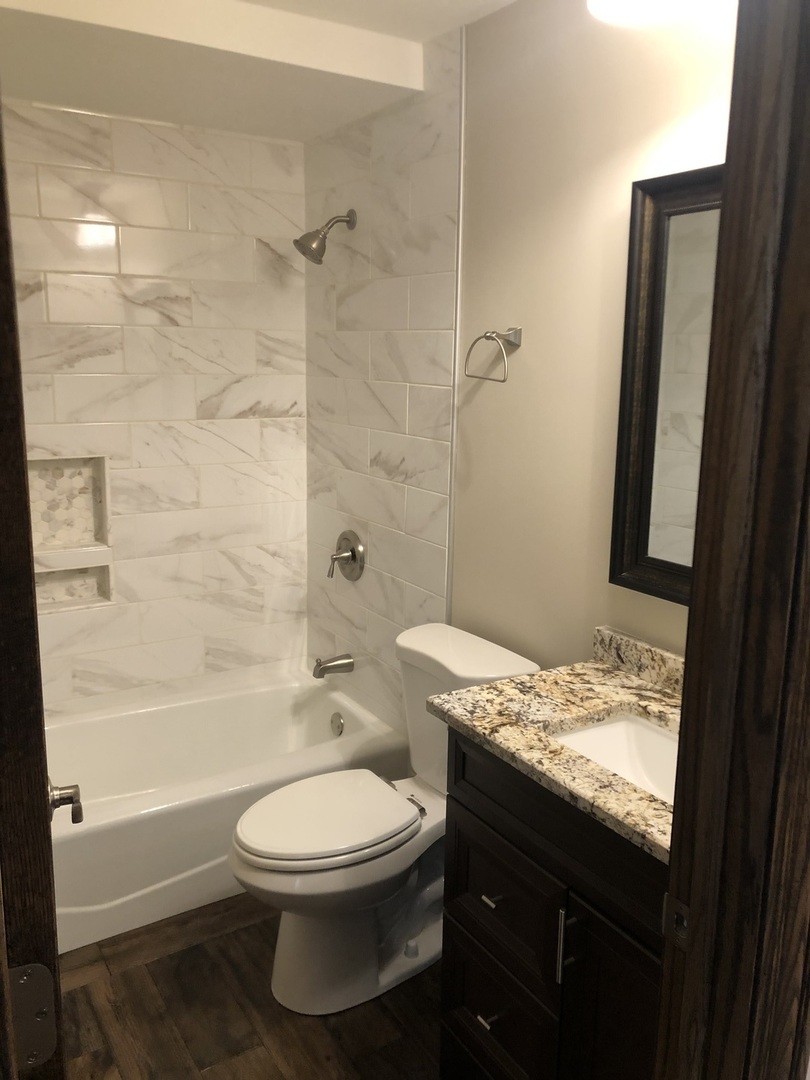 10301 McVicker Avenue Chicago Ridge, IL 60415 - Photo 9 of 21 a bathroom with a granite countertop toilet a sink and a bathtub