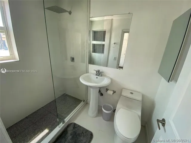 a bathroom with a sink a toilet a mirror and shower