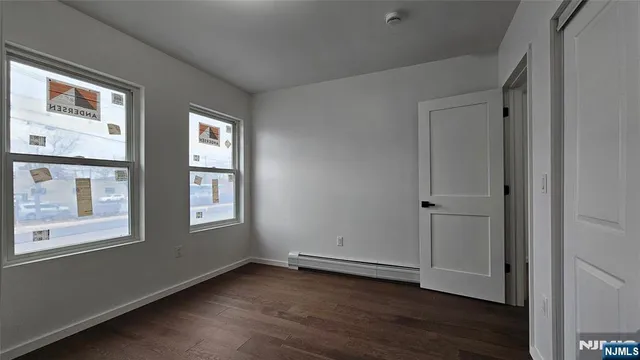 a view of an empty room with wooden floor and windows