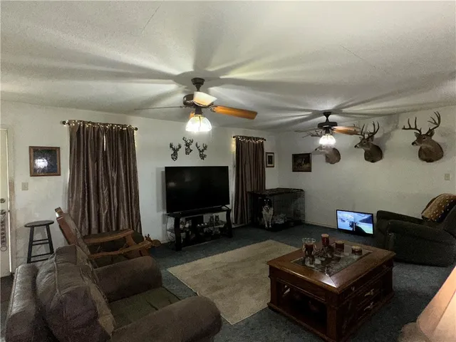 a living room with furniture a ceiling fan and a flat screen tv