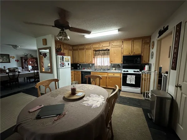 a kitchen with stainless steel appliances granite countertop a sink refrigerator dining table and chairs