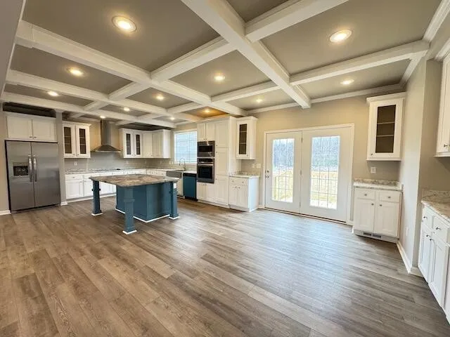 a large white kitchen with stainless steel appliances kitchen island granite countertop a stove and a refrigerator