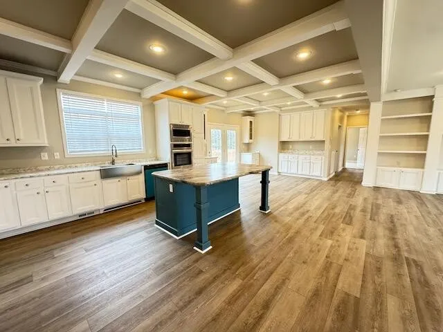 a large white kitchen with wooden floors and white stainless steel appliances