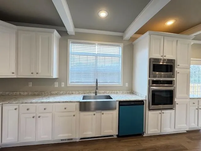 a kitchen with granite countertop a sink stainless steel appliances and white cabinets